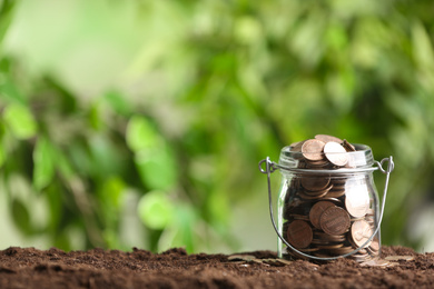 Coins on soil against blurred background, space for text. Money savings