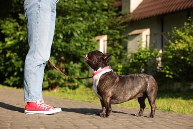 Photo of Woman walking with cute French Bulldog outdoors, closeup