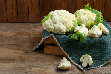 Crate with cut and whole cauliflowers on wooden table. Space for text