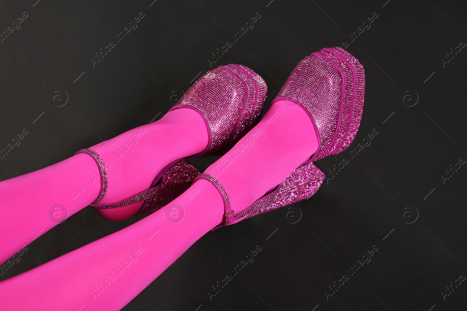 Photo of Woman wearing pink tights and high heeled shoes with platform and square toes on black background, closeup