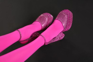 Photo of Woman wearing pink tights and high heeled shoes with platform and square toes on black background, closeup