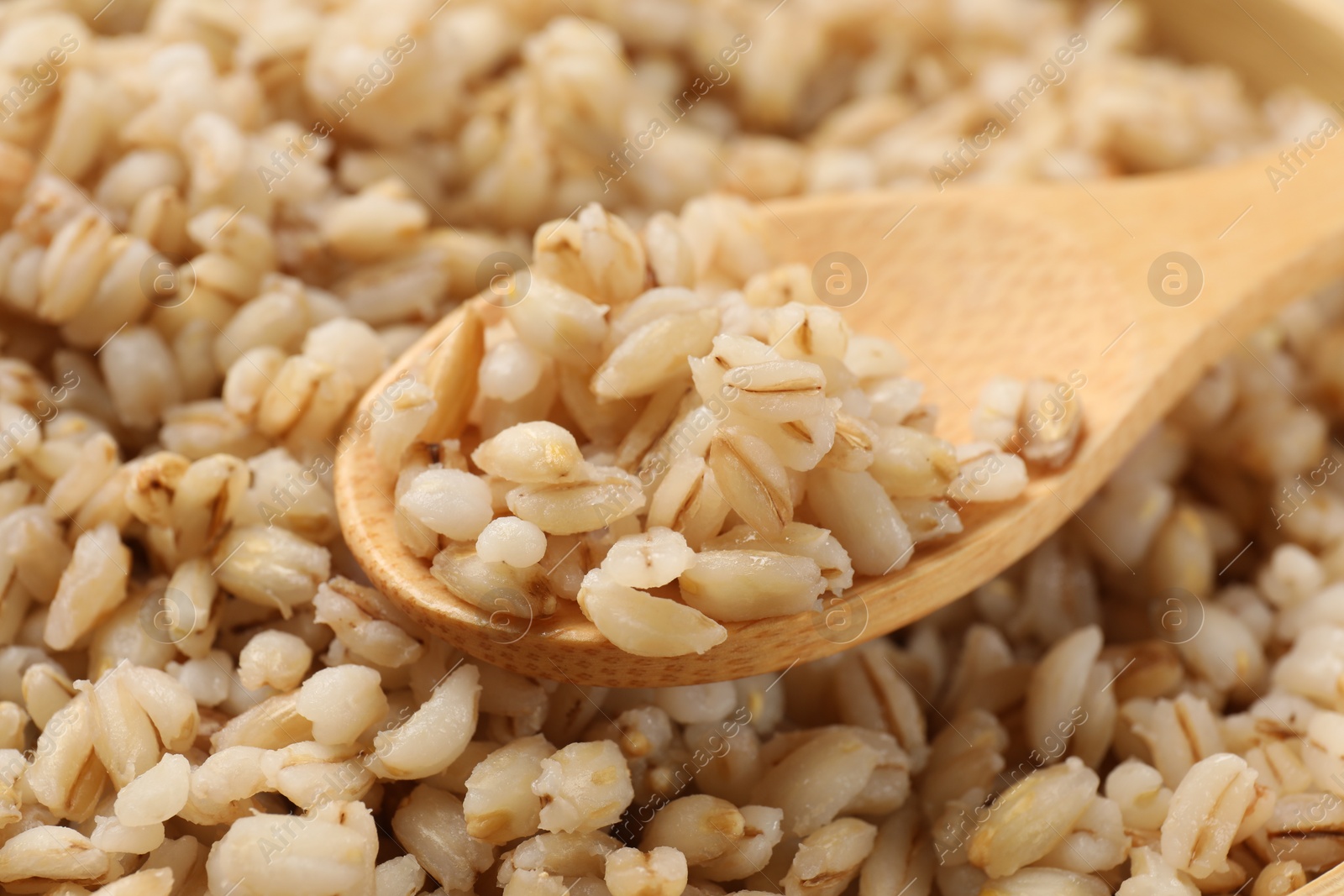 Photo of Delicious pearl barley and wooden spoon, closeup