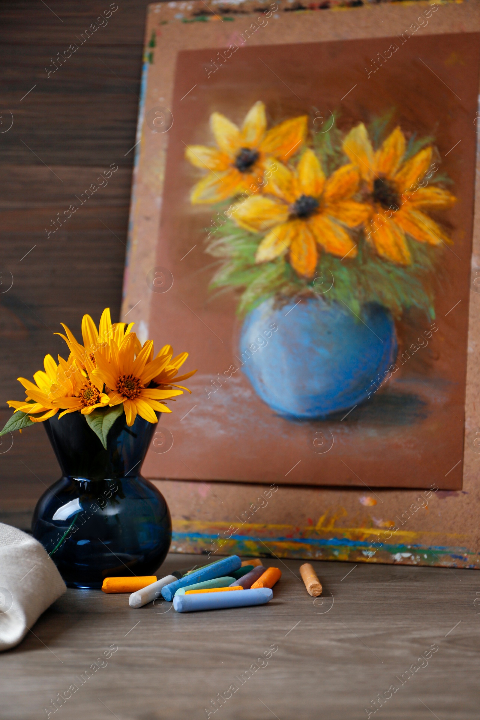 Photo of Yellow flowers, beautiful drawing and set of colorful pastels on wooden table