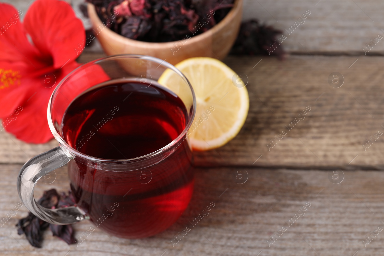 Photo of Cup of delicious hibiscus tea on wooden table, closeup. Space for text