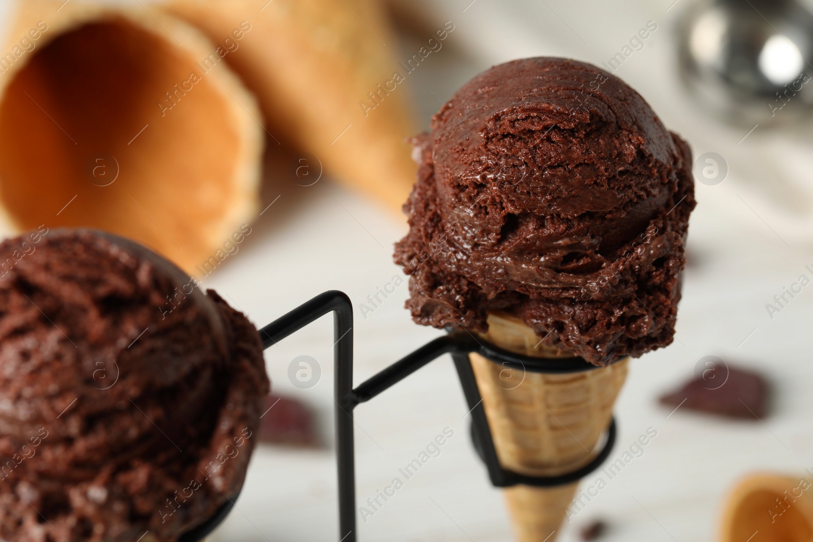 Photo of Chocolate ice cream scoops in wafer cones on stand, closeup