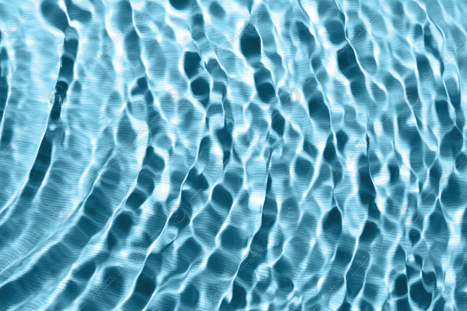 Image of Rippled surface of clear water on light blue background, closeup