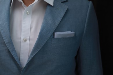 Man with handkerchief in suit pocket on black background, closeup