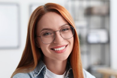 Photo of Portrait of beautiful young woman with red hair indoors. Attractive lady smiling and looking into camera