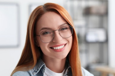 Portrait of beautiful young woman with red hair indoors. Attractive lady smiling and looking into camera