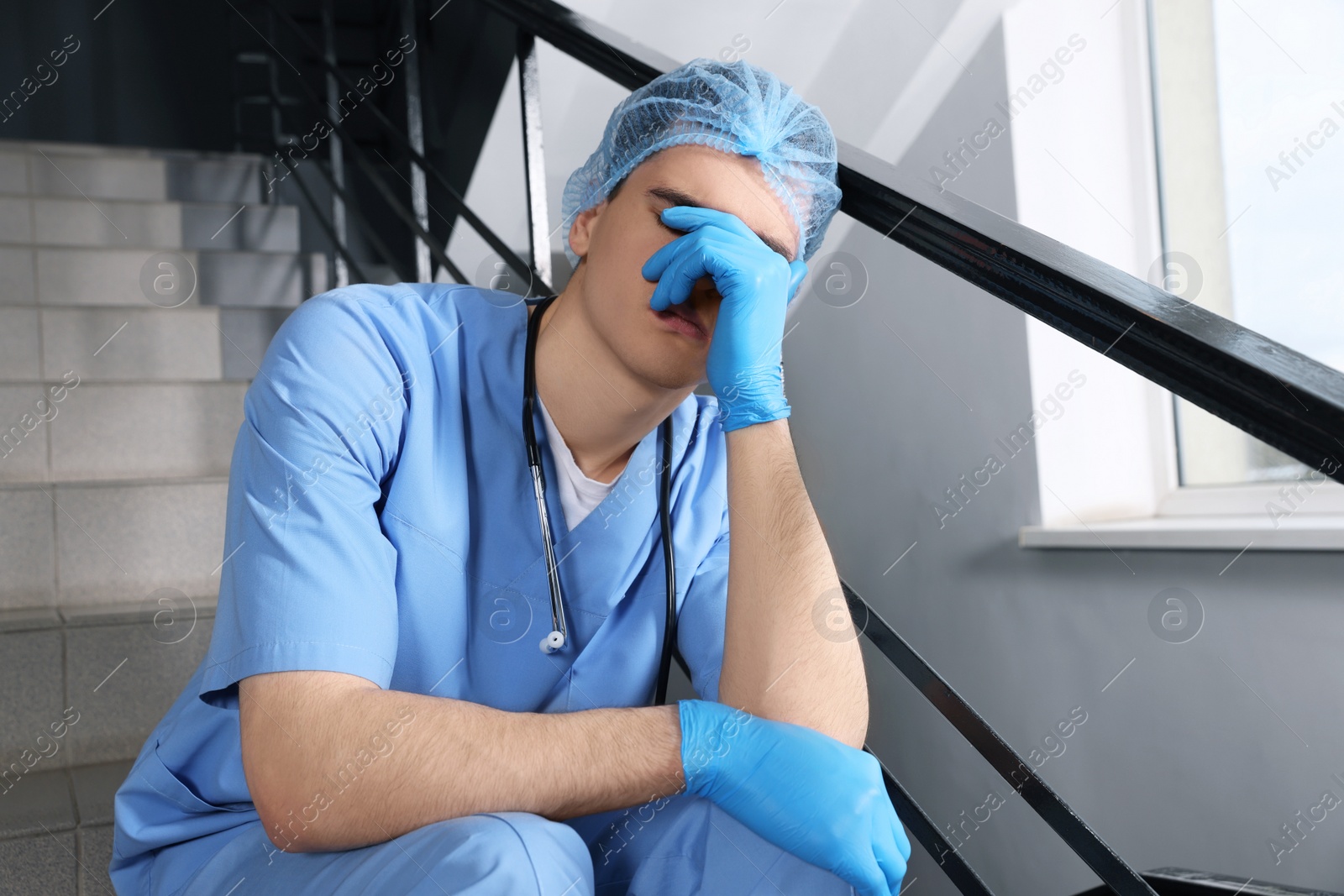 Photo of Exhausted doctor sitting on stairs in hospital