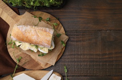 Photo of Tasty brie cheese sandwich on wooden table, flat lay. Space for text
