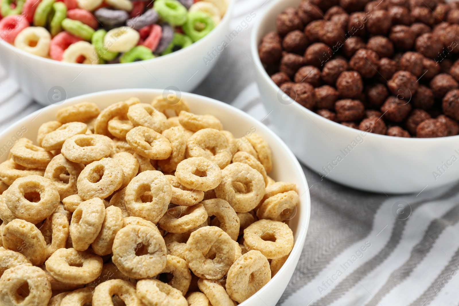 Photo of Different delicious breakfast cereals on kitchen towel, closeup