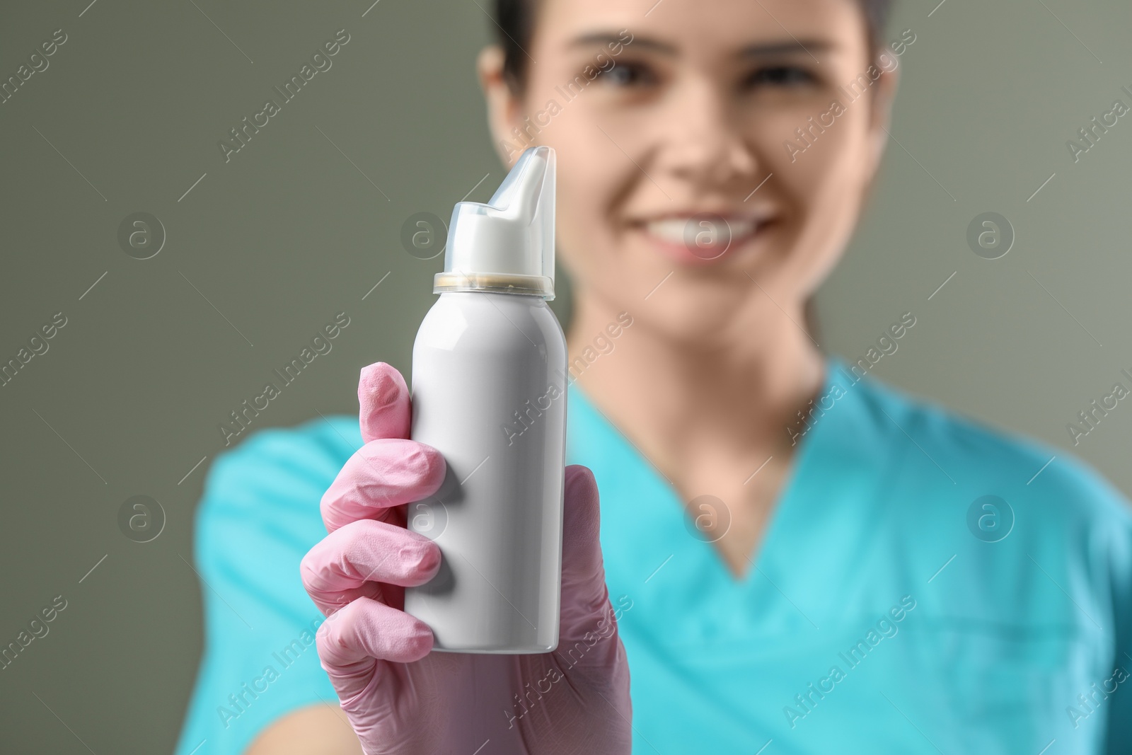Photo of Woman holding nasal spray bottle on olive background, selective focus