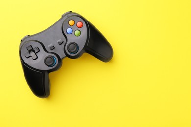 Wireless game controller on yellow background, top view. Space for text