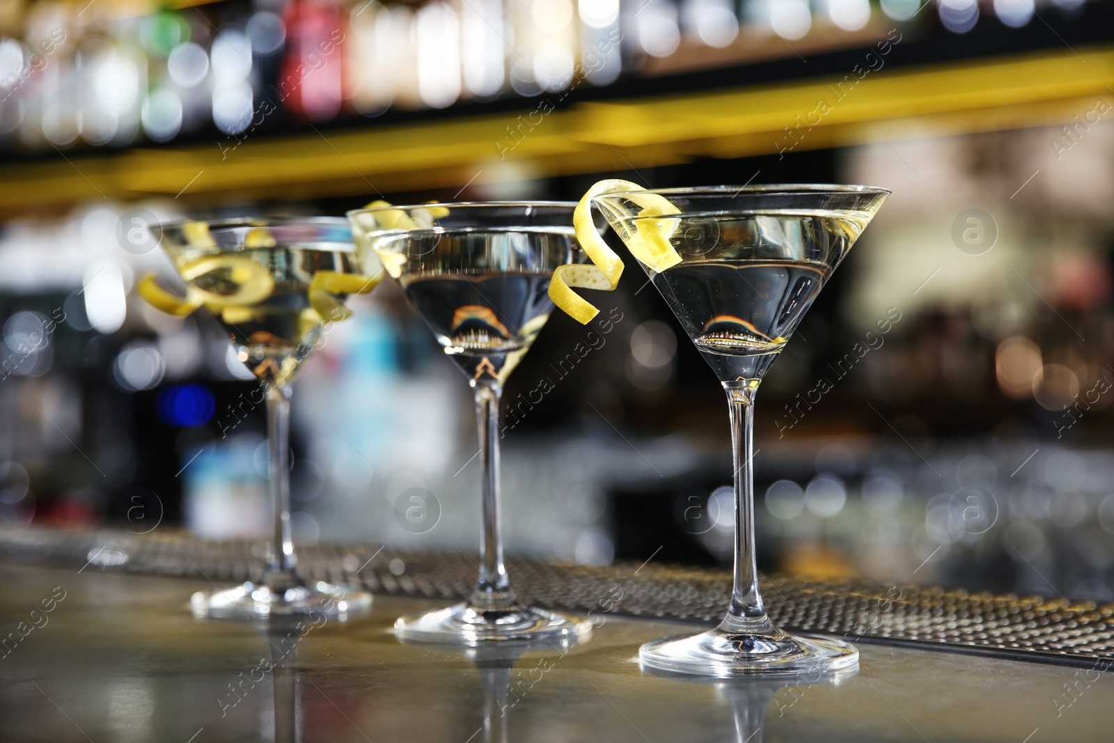 Photo of Glasses of lemon drop martini cocktail on bar counter. Space for text