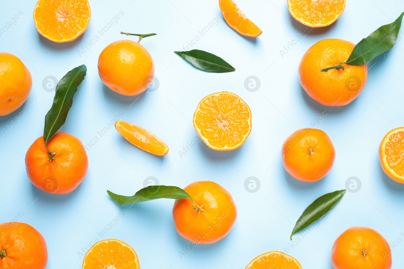 Photo of Flat lay composition with fresh ripe tangerines and leaves on light blue background. Citrus fruit