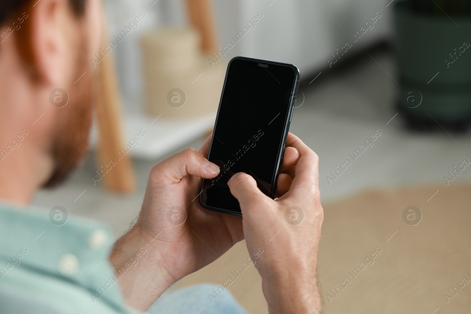 Photo of Man using smartphone at home, closeup view. Space for text