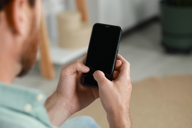 Man using smartphone at home, closeup view. Space for text