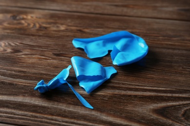 Photo of Popped blue latex balloon on wooden background