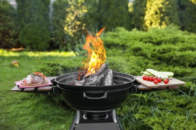 Photo of Raw meat and vegetables on table near barbecue grill outdoors