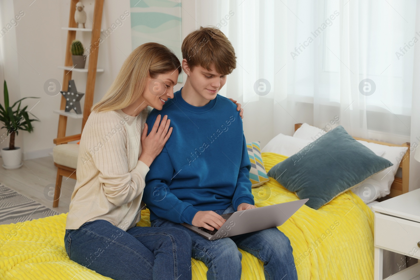 Photo of Happy mother and her teenage son with laptop at home