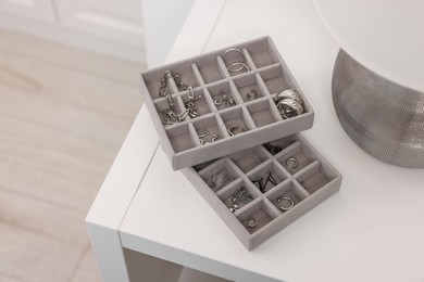 Photo of Jewelry boxes with many silver accessories on white table, above view