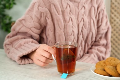 Photo of Woman with cup of tea at wooden table, closeup