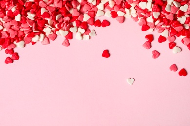 Heart shaped sprinkles on pink background, flat lay. Space for text