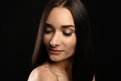 Portrait of pretty young woman with gorgeous chestnut hair on black background