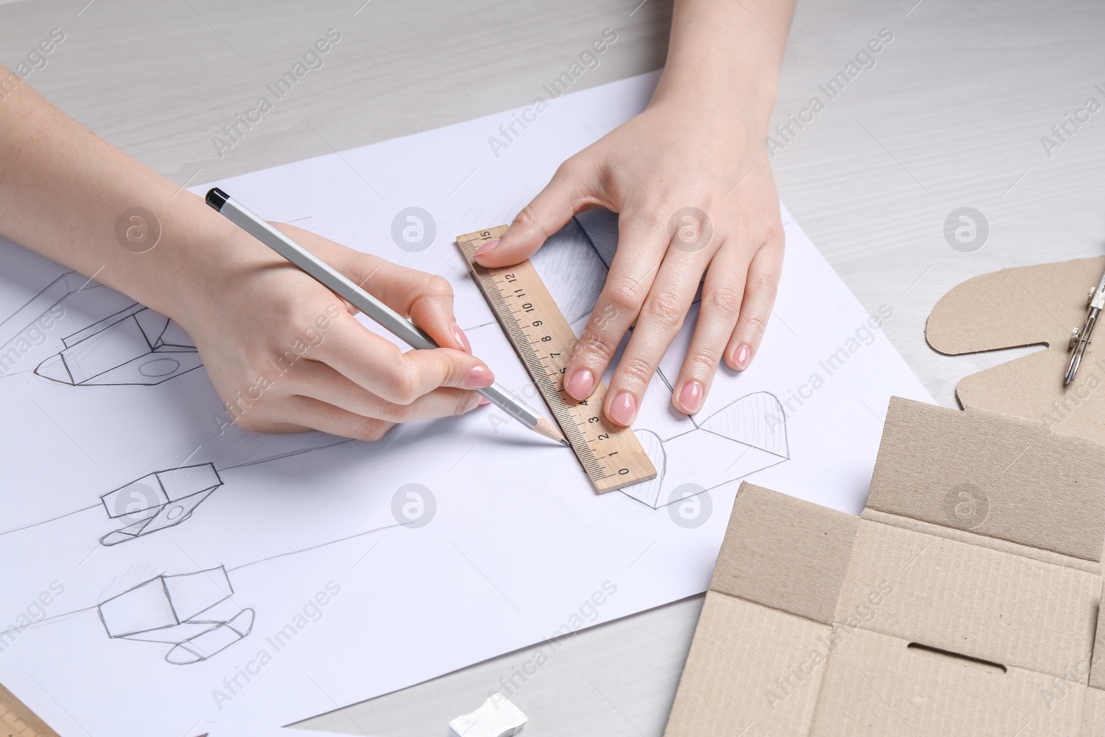 Photo of Woman creating packaging design at light wooden table, closeup