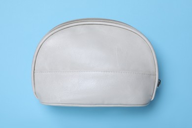 White leather cosmetic bag on light blue background, top view