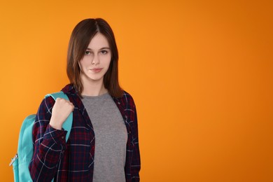 Photo of Portrait of cute teenage girl with backpack on orange background. Space for text