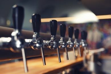Row of shiny beer taps in pub