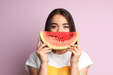 Beautiful young woman posing with watermelon on color background