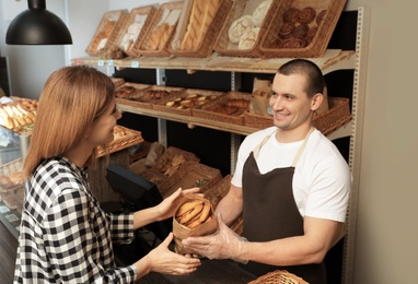 Photo of Woman buying tasty pastry in bakery shop