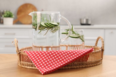 Photo of Refreshing cucumber water with rosemary in jug and glass on wooden table