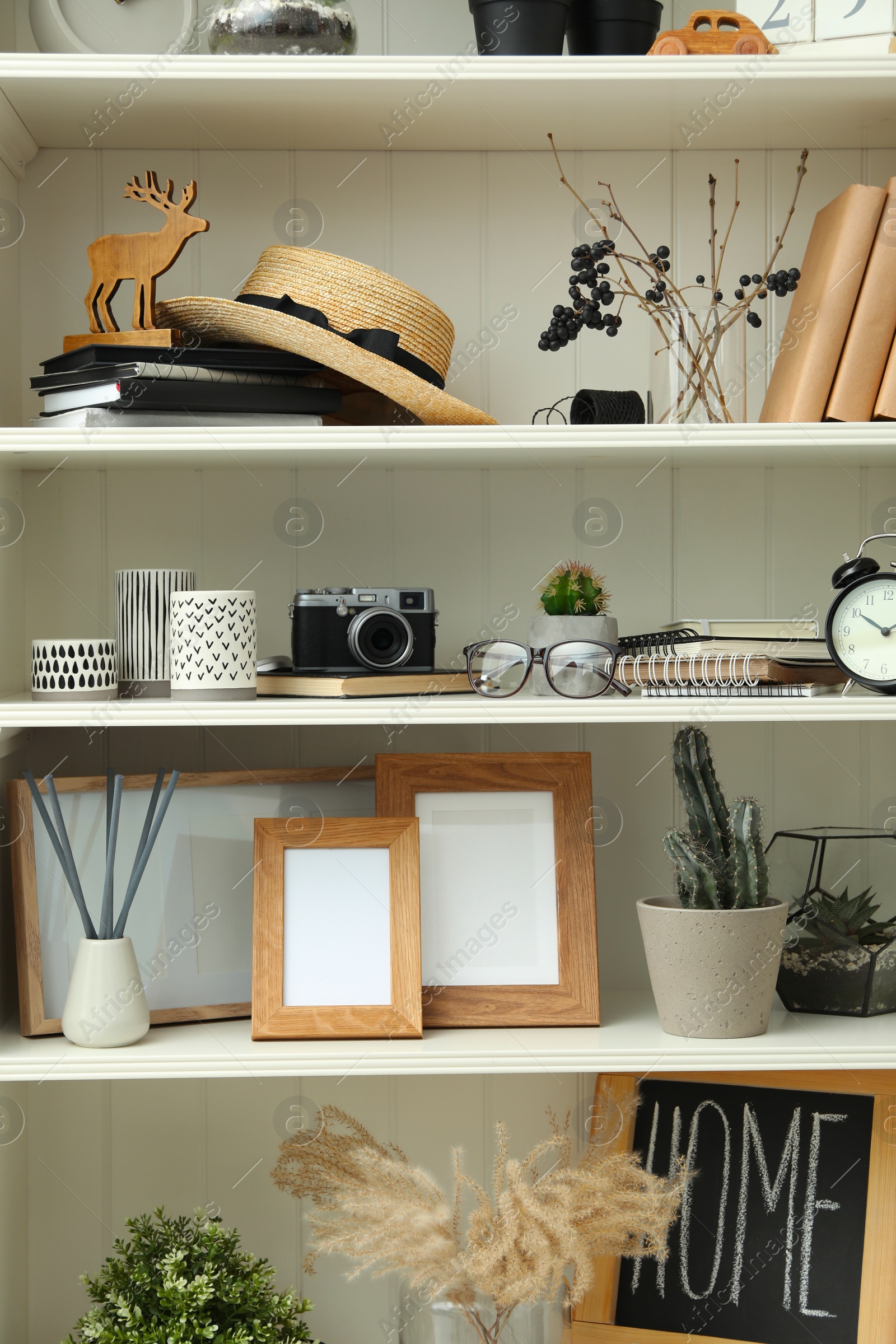 Photo of White shelving unit with photo frames and different decorative elements