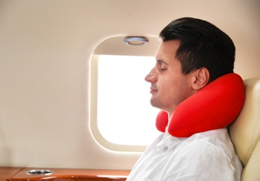 Handsome man with neck pillow sleeping during flight. Ait travel