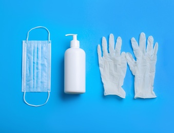 Photo of Medical gloves, mask and hand sanitizers on light blue background, flat lay
