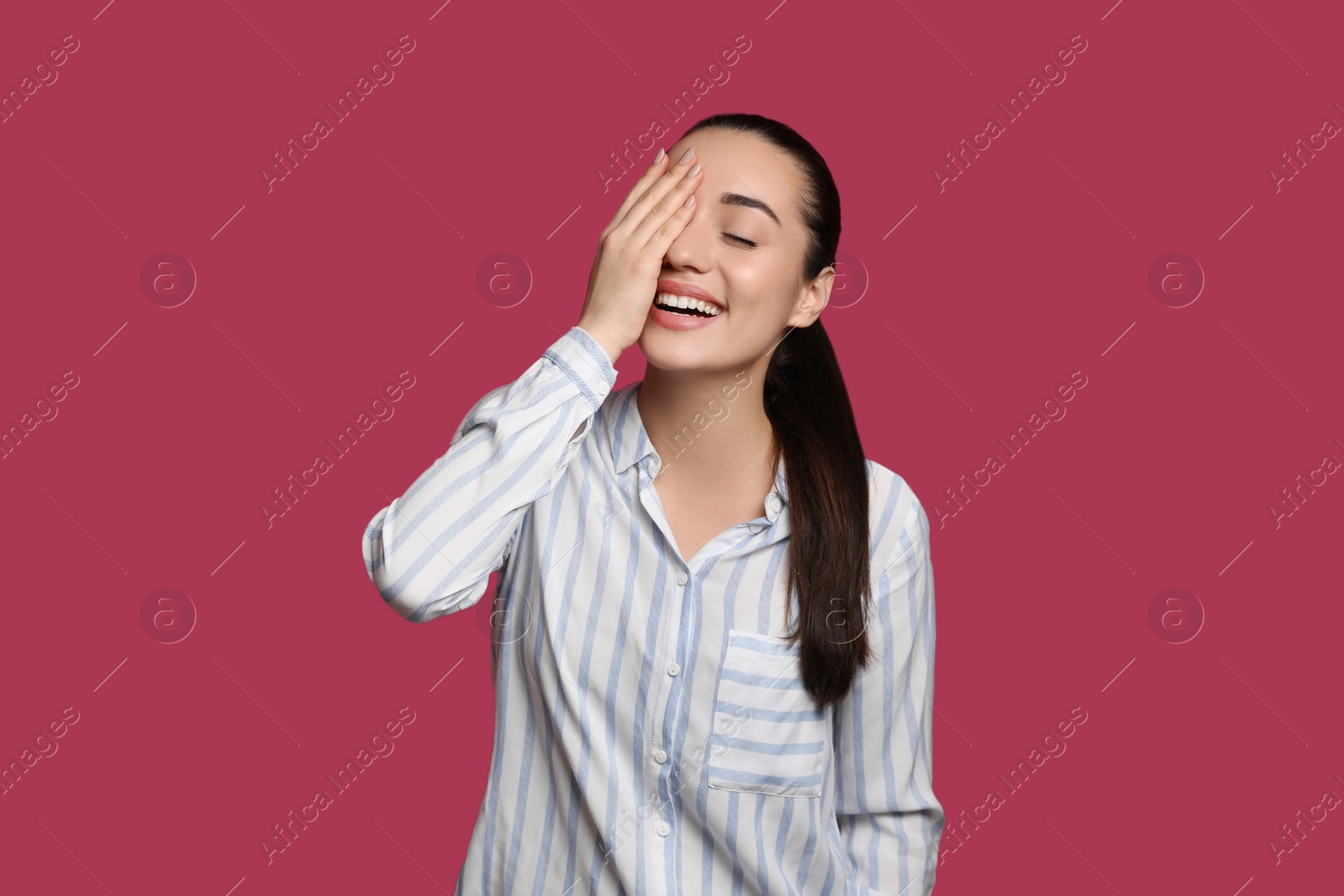 Photo of Beautiful young woman laughing on maroon background. Funny joke