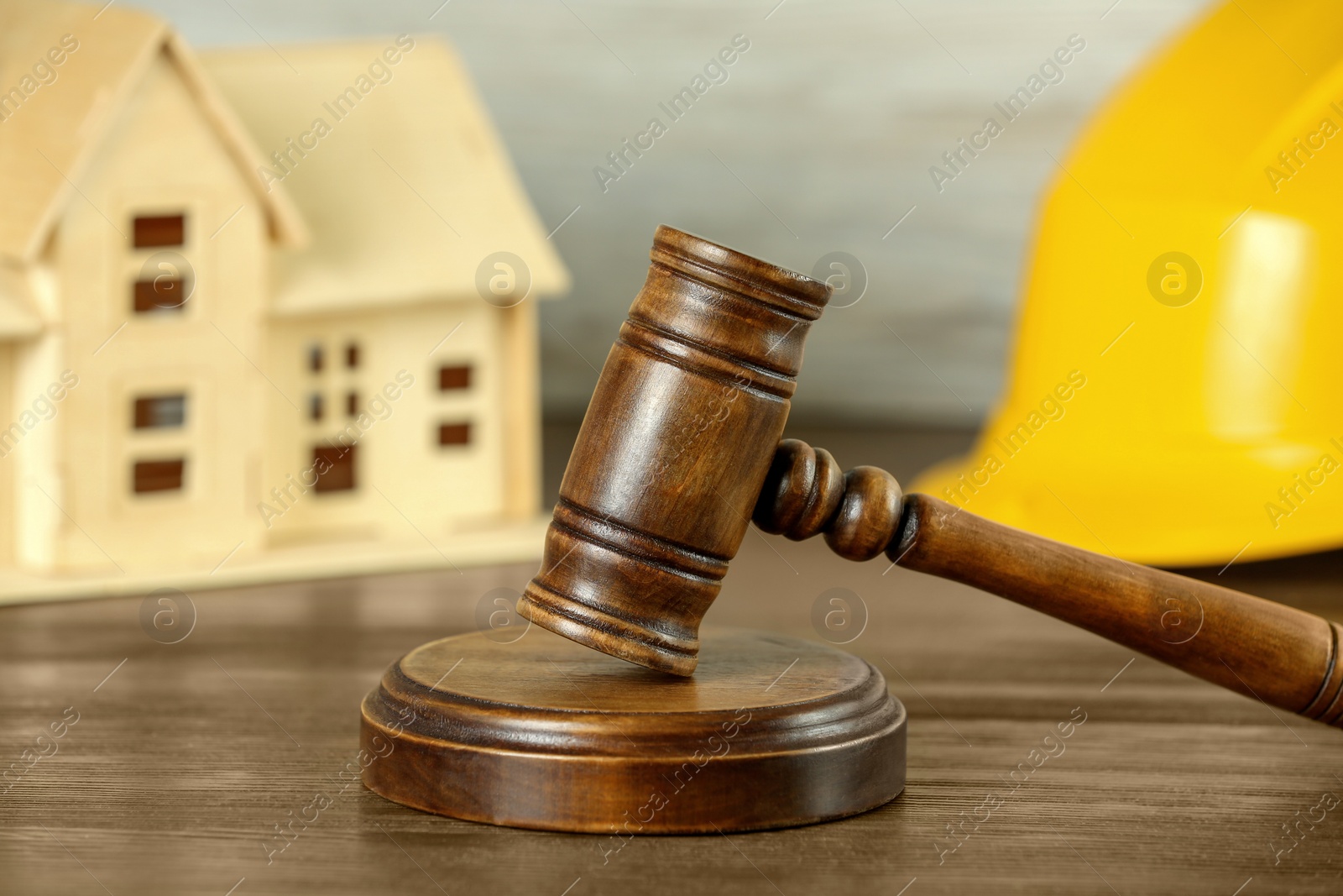 Photo of Construction and land law concepts. Judge gavel, hardhat with house model on wooden table