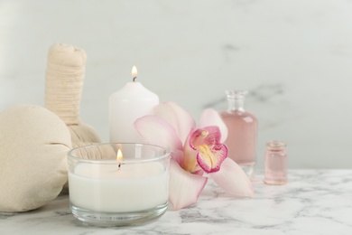 Beautiful spa composition with candles and aroma oil on white marble table