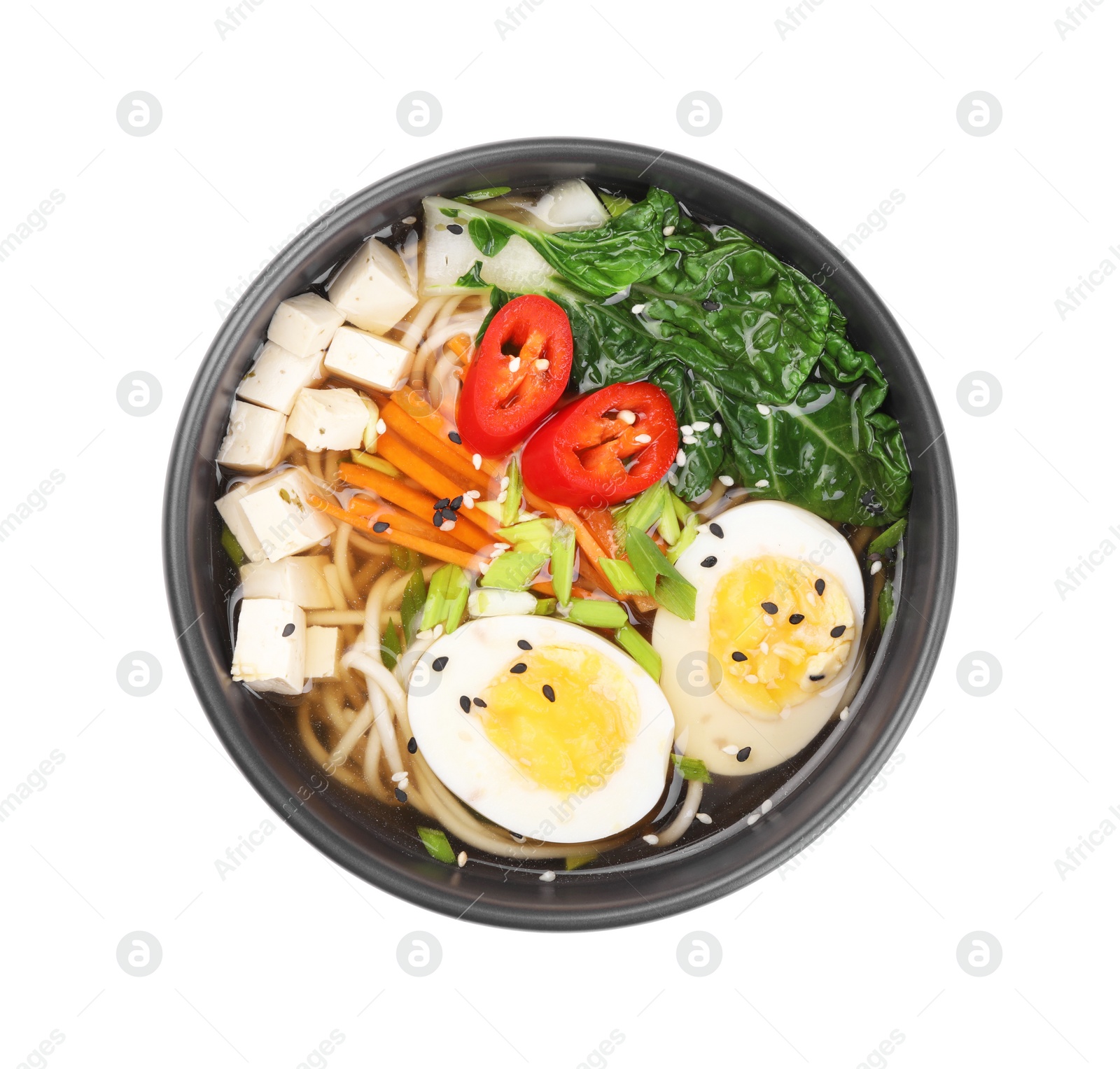 Photo of Delicious vegetarian ramen with egg, mushrooms, tofu and vegetables in bowl isolated on white, top view. Noodle soup