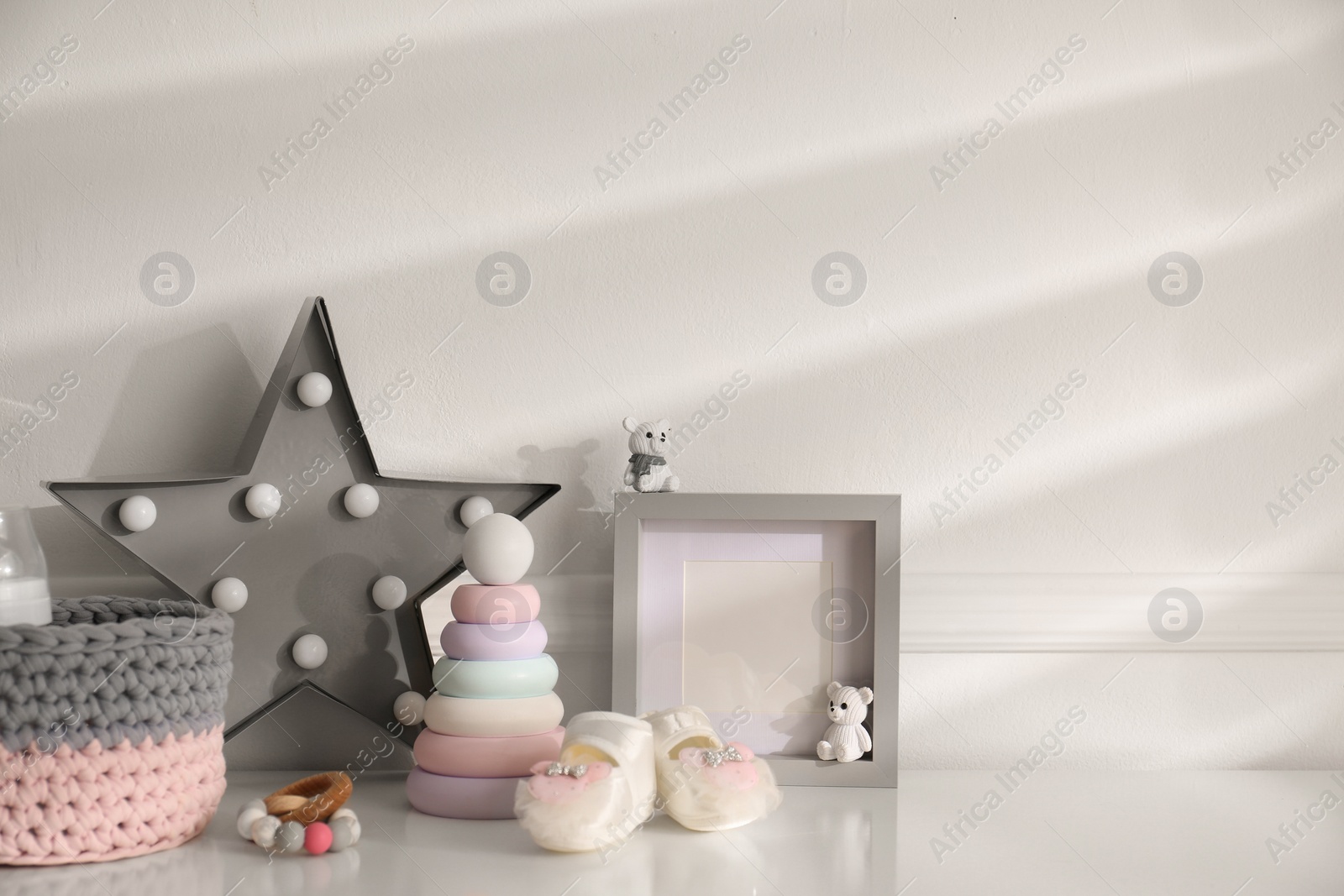 Photo of Different baby accessories and toys on white table in child room, space for text. Interior design