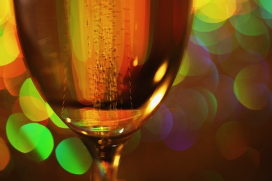 Photo of Glass of champagne with golden bubbles on blurred background, closeup
