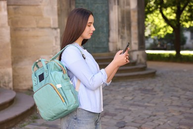 Photo of Travel blogger using smartphone on city street