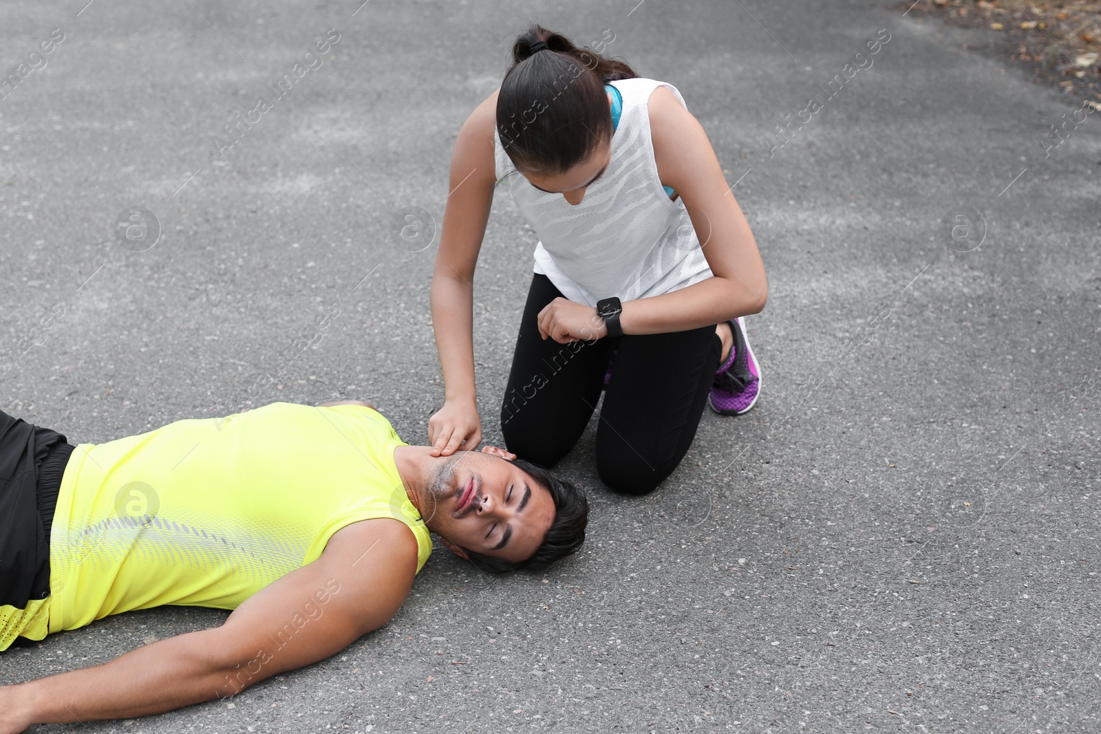 Photo of Young woman checking pulse of unconscious man on street. Space for text