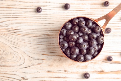 Photo of Dish with fresh acai berries on wooden table, top view