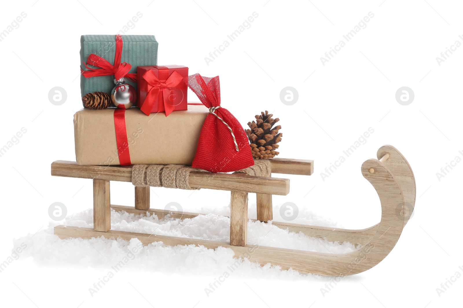 Photo of Wooden sleigh with gifts, pine cones, Christmas ball and artificial snow on white background