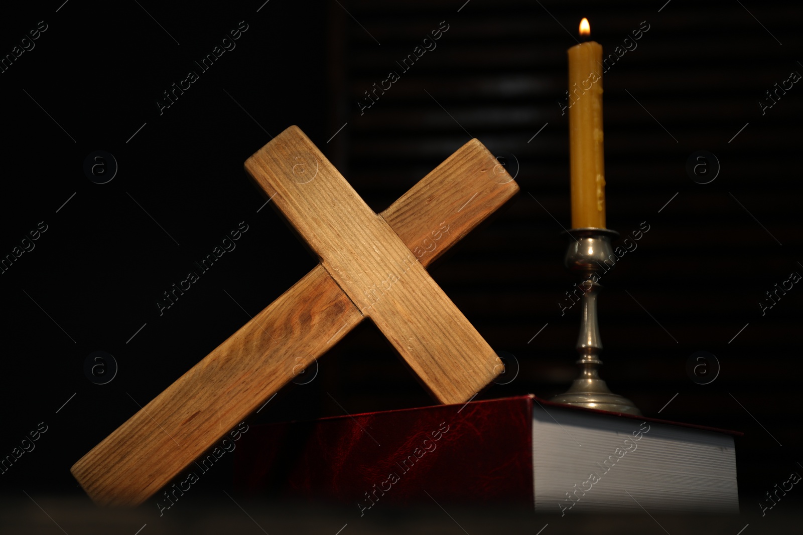 Photo of Church candle, Bible and wooden cross on table